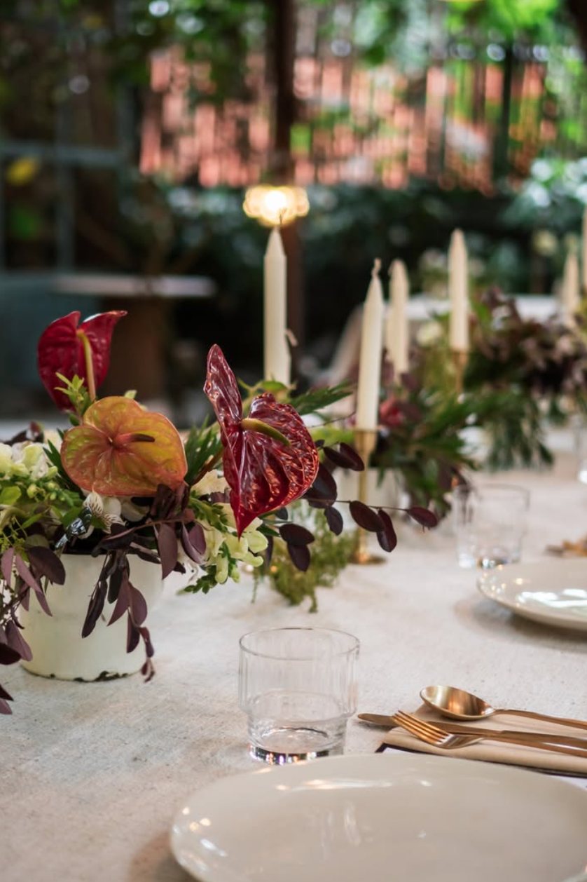 Flower-filled table with candles and anthuriums